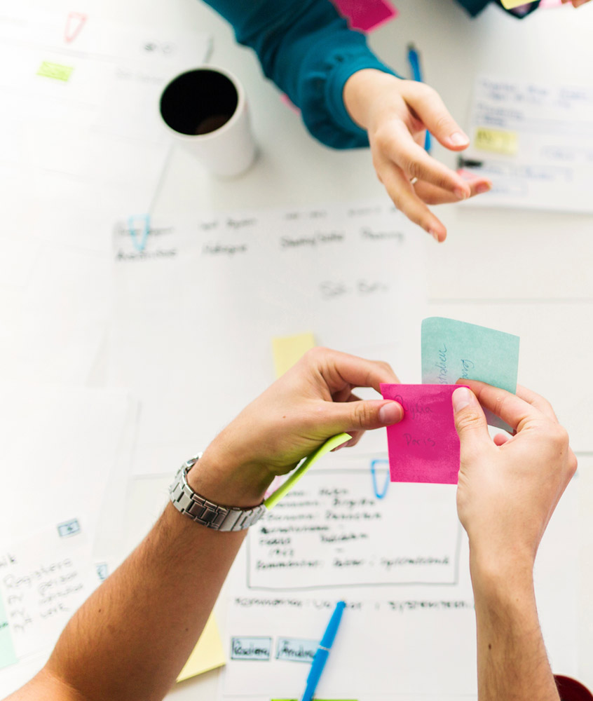 closeup of 2 sets of hands, working with notes during a planning meeting